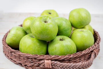 Group of ripe green apples in a basket on white background