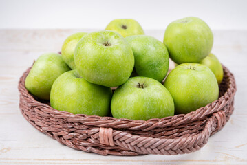 Group of ripe green apples in a basket on white background
