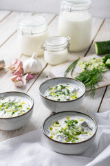 Traditional summer cold soup of homemade yogurt, cucumbers and fresh herbs on a table