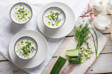 Traditional summer cold soup of homemade yogurt, cucumbers and fresh herbs on a table