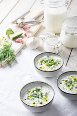 Traditional summer cold soup of homemade yogurt, cucumbers and fresh herbs on a table