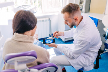 close up of dentist with phone showing teeth x-ray to female pat © Ivan