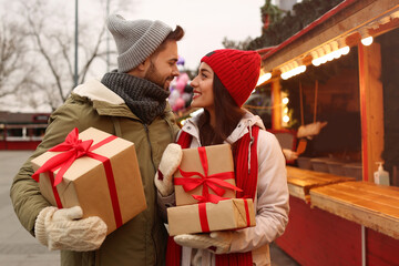 Fototapeta premium Lovely couple with Christmas presents at winter fair