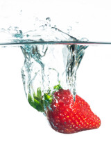 Strawberry falling in water. Splashing water