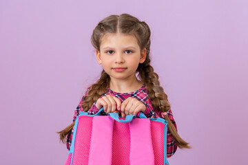 A schoolgirl holds a school bag in front of her.