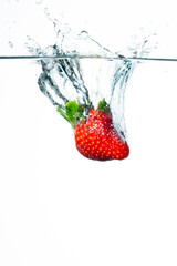 Strawberry falling in water. Splashing water