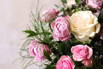 Beautiful bouquet with roses on beige background, closeup