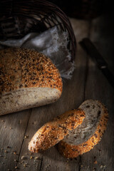 Fresh bread with seeds in a wicker basket on a rustic table