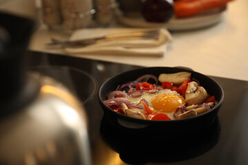 Frying pan with tasty egg and vegetables on stove, space for text