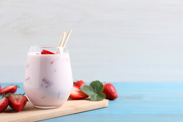 Delicious drink with strawberries on light blue wooden table, space for text