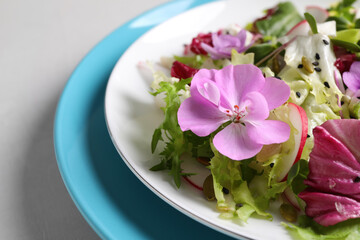 Fresh spring salad with flowers on grey table, closeup