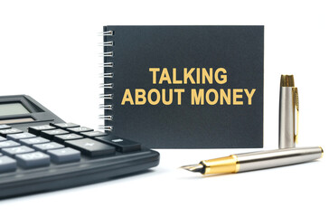 On a white background, there is a calculator, a pen and a black notebook with the inscription - TALKING ABOUT MONEY