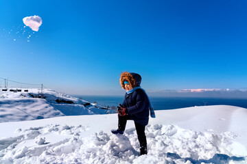 Boy playing snowballs in winter