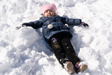 Fototapeta na wymiar Girl lies in the snow in winter