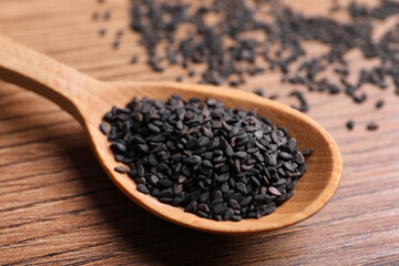 Black sesame seeds on wooden table, closeup
