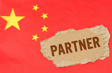 Against the background of the Chinese flag lies cardboard with the inscription - partner