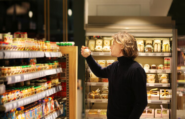Young man shopping in supermarket, reading product information