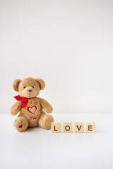 Valentine's day teddy bear and wooden letters with the inscription love. Place for an inscription.
