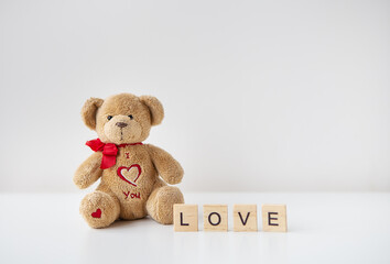 Valentine's day teddy bear and wooden letters with the inscription love. Place for an inscription.