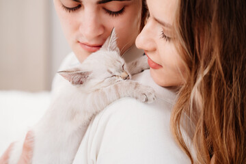 A beautiful couple of young lovers holding a small white kitten. 