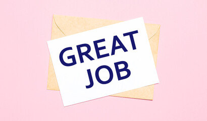 On a light pink background - a craft envelope. It has a white sheet of paper that says GREAT JOB.