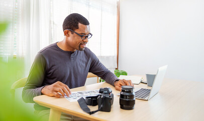 Portrait of African photographer black man working in office holding camera with laptop. Business people employee freelance online marketing.  Successful freelance creative artist men business concept