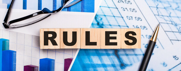 On the bright diagrams, glasses, a pen and wooden cubes with the word RULES. Business concept