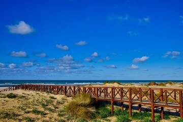 Wooden road to the beach over the dunes under a blue sky