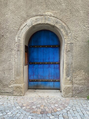 Fototapeta na wymiar Altes Rundtor mit schwerer Holztür mit Eisenstreben blau angestrichen