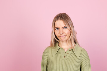 Obraz premium Pretty european woman in casual sweater on pink background suffering unhappy with gloomy expression needs support and help