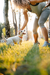 Sporty girl plays with pet dog in the park outdoors in summer.