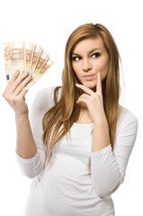 What to buy - excited smiling girl with money. Young happy woman in white pullover holding fan of Euro bills currency and thinking about shopping. Isolated on white background, studio shot.