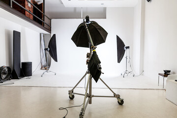 Empty photo studio with lighting equipment. Photographer workplace interior with professional tool set gear. Flash light white background scenes ready for studio shooting. Modern photographer studio