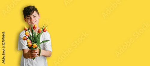 Concept of mothers day. happy boy holds beautiful bouquet of yellow tulips. holidays banner for March 8th, International Women's Day, Mother's Day with space for text.