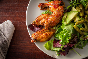 top view of a plate with roasted chicken wings and salad