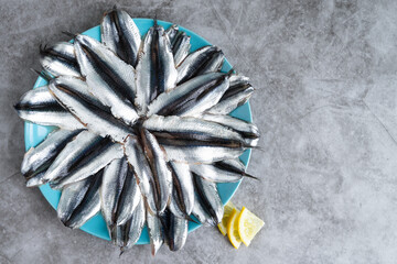 Dish full of anchovies on marble bottom. Copy space.