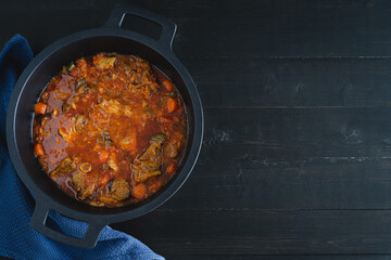 Casserole with lamb stew on black background. Copy space.