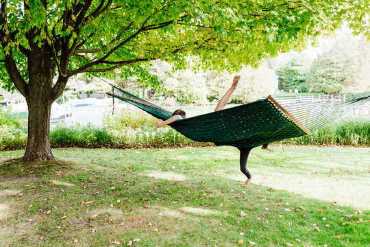 Young children trying to balance hammock outdoors
