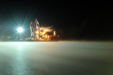 Murmansk, Russia - February 04, 2012: Icebreaker Zapolyarny on the water covered with a blanket of snow. An icebreaker stands in the port, lit by lanterns, in the early morning. Wallpaper.
