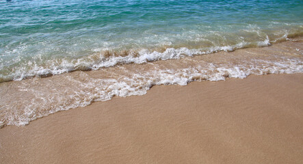 Fototapeta na wymiar foamy gentle turquoise waves against sand