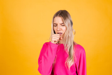 Pretty european woman in pink blouse on yellow background feeling unwell and coughing as symptom for cold or bronchitis