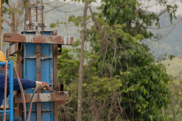Workers were letting gas cut the steel from the dry concrete columns. Has a background of trees and branches