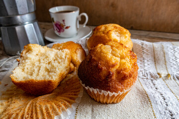 Cupcakes accompanied with coffee, on a napkin, on a rustic wooden background. 