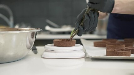 Chef pouring freshly made chocolate in desert base, kitchen background