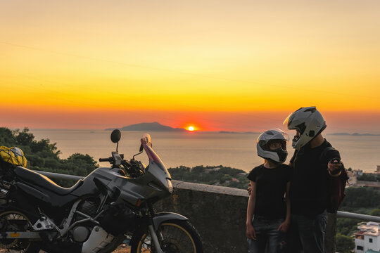 Beautiful couple in love and motorcycle on the street, outdoor portrait, travel together, Sunset over the Capri island, sea and mountains. Journey vacation