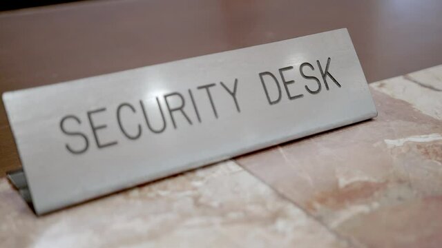 Close up of a security desk plaque.  The camera rack focuses utilizing a shallow depth of field to feature the sign.