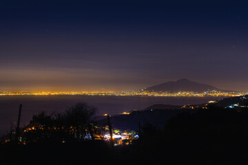 Mount Vesuvius and the lights of the city of Naples from a great distance. Night view. Space to insert text. Sea and tranquility Tourism