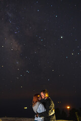 Fototapeta na wymiar Couple traveler enjoying watched the star and milky way galaxy over the sky on top of the mountain. Night landscape with beautiful sky. Vertical photo