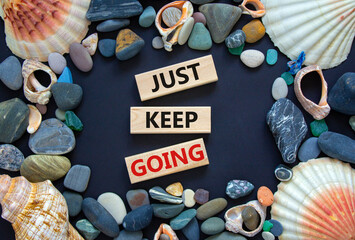 Just keep going symbol. Wooden blocks with words 'Just keep going'. Beautiful black background, seashells and sea stones. Business, just keep going concept, copy space. - obrazy, fototapety, plakaty