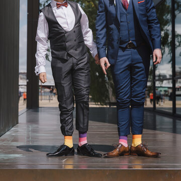 Homosexual newlyweds celebrating happy wedding day wearing black and blue suits.